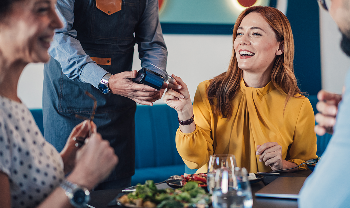 Businesswoman paying with credit card during lunch with the colleagues.