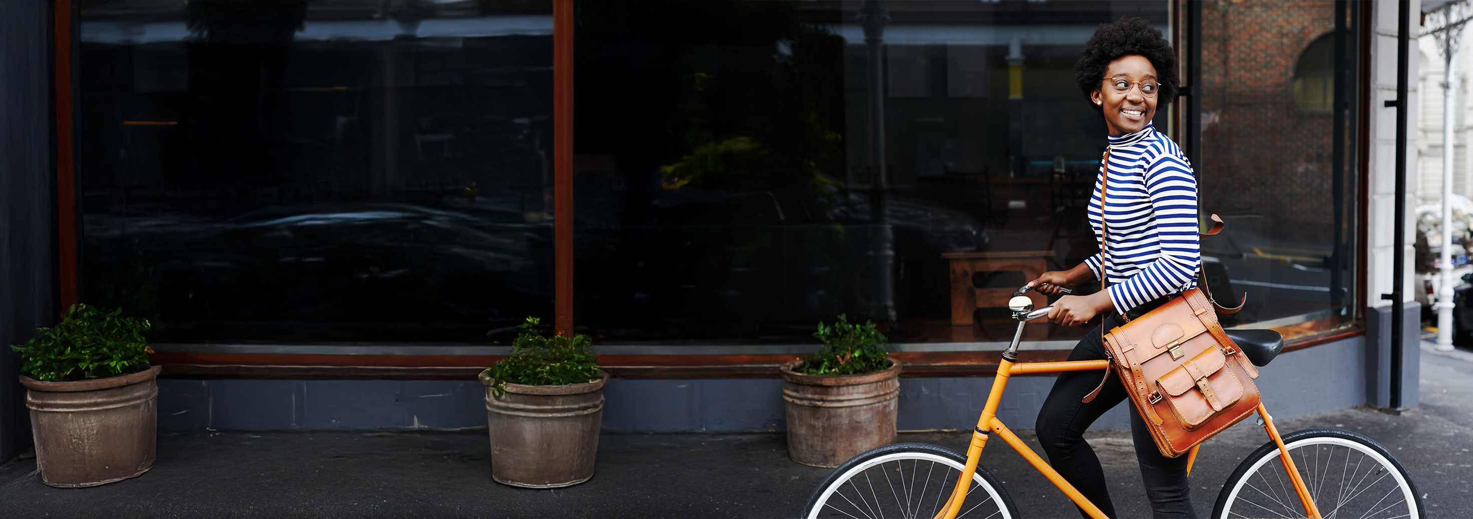 A young woman is walking next to her bicycle and smiling after using our 401k calculator to estimate how much her plan may accumulate.