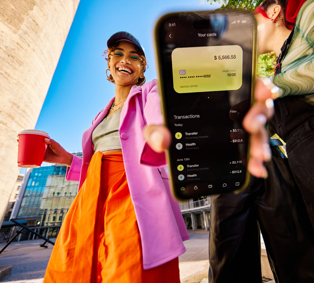 young adult woman outside showing her bank account information on her phone