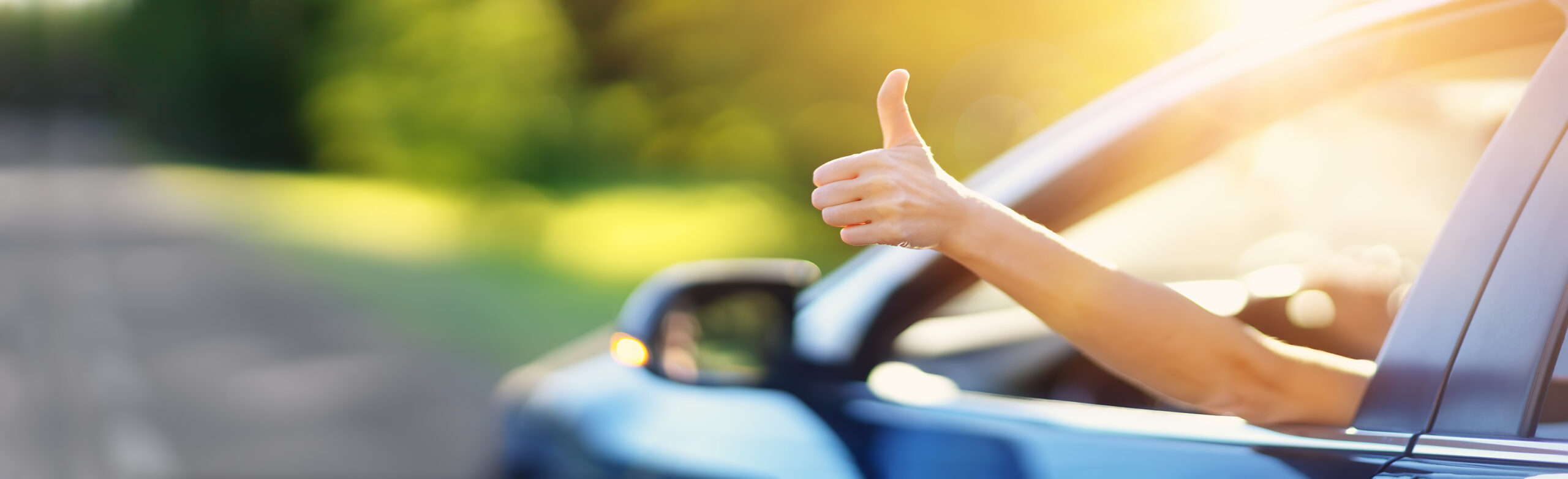 A person is giving a thumbs up out of a car window because they're happy they prequalified through Auto Loan Recapture to refinance their vehicle