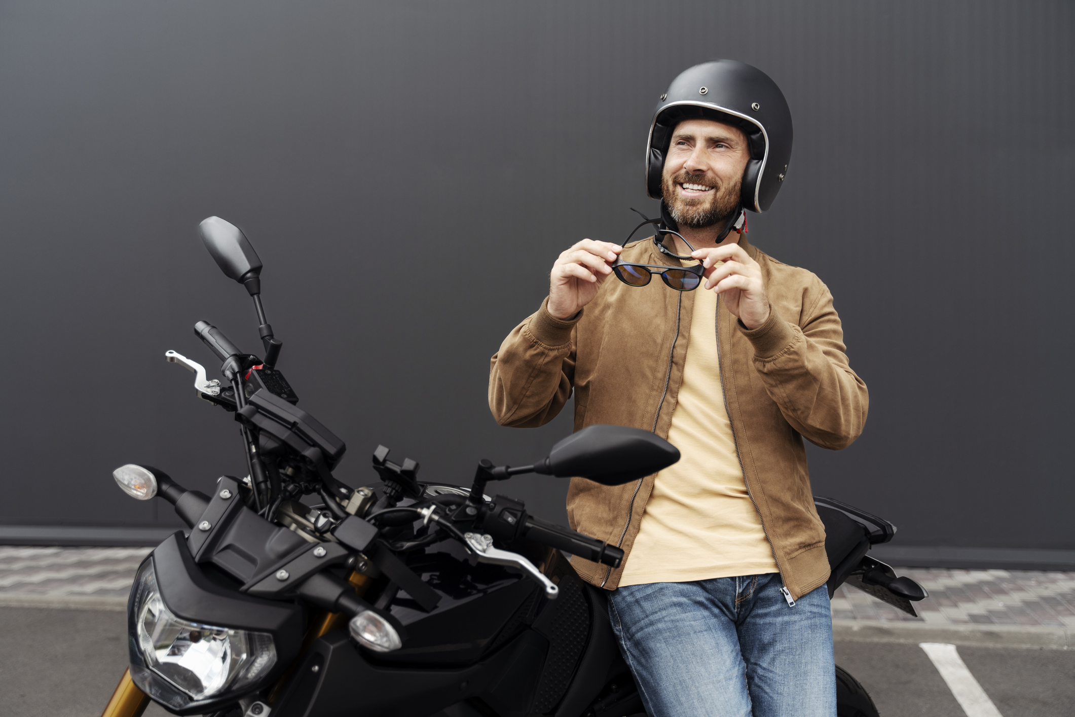 A man wearing a helmet and a leather jacket leans against his motorcycle after using PACU for his boat, RV, or motorcycle loan.
